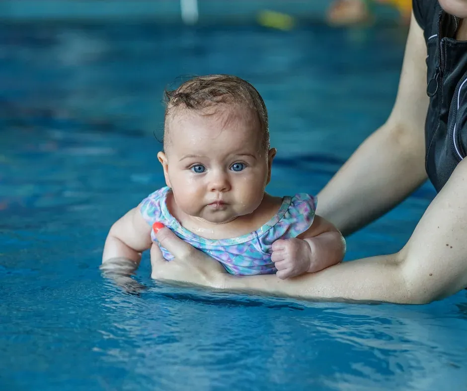 Instructor guiando a bebé en clase de natación