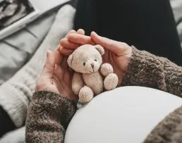 Madre embarazada sosteniendo su vientre, símbolo de esperanza y amor tras una pérdida perinatal.