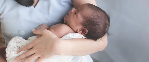 A mom carrying her baby with one arm.