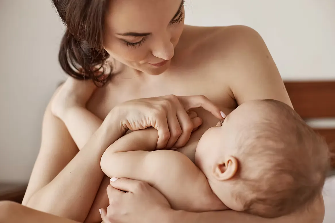 Mamá amamantando a su bebé mientras lo abraza.