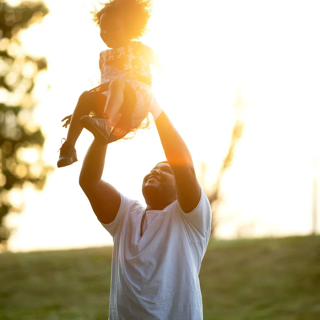 Papá sostiene a su hija en el parque.
