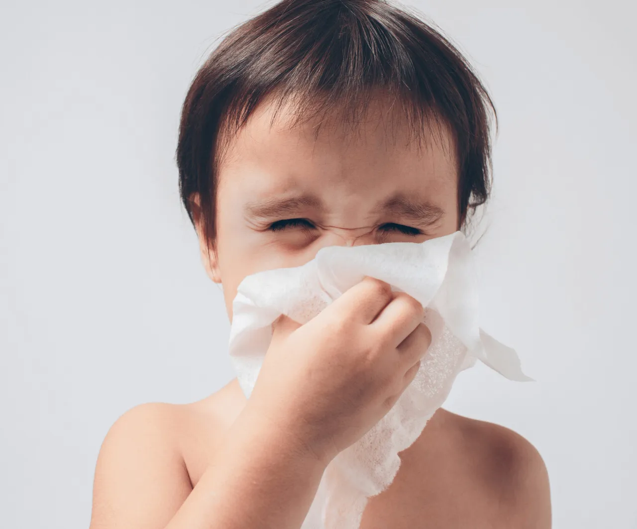 Niña con congestión nasal soplandose la nariz