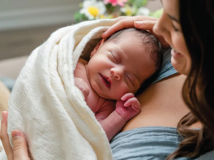 Madre abrazando a su bebé recién nacido envuelto en una manta