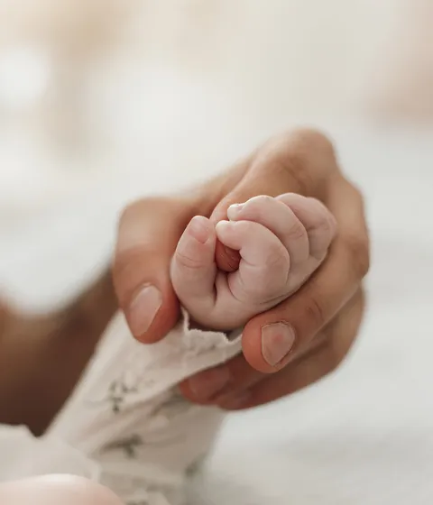 Mano de adulto sosteniendo la mano de un bebé