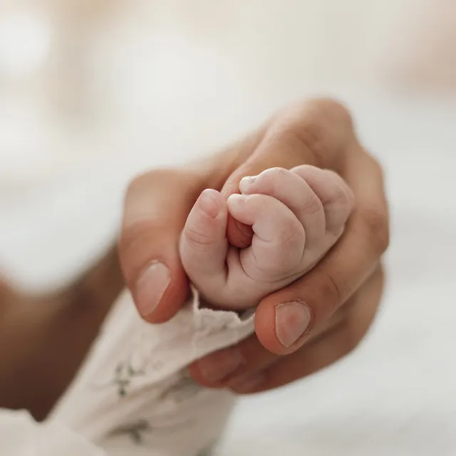 Mano de adulto sosteniendo la mano de un bebé