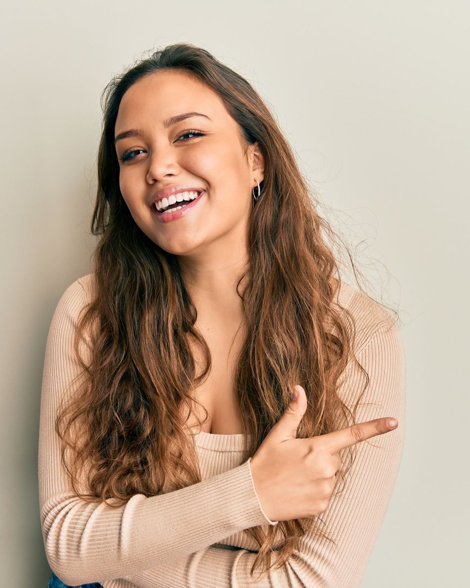 Mujer joven sonriendo y señalando con entusiasmo