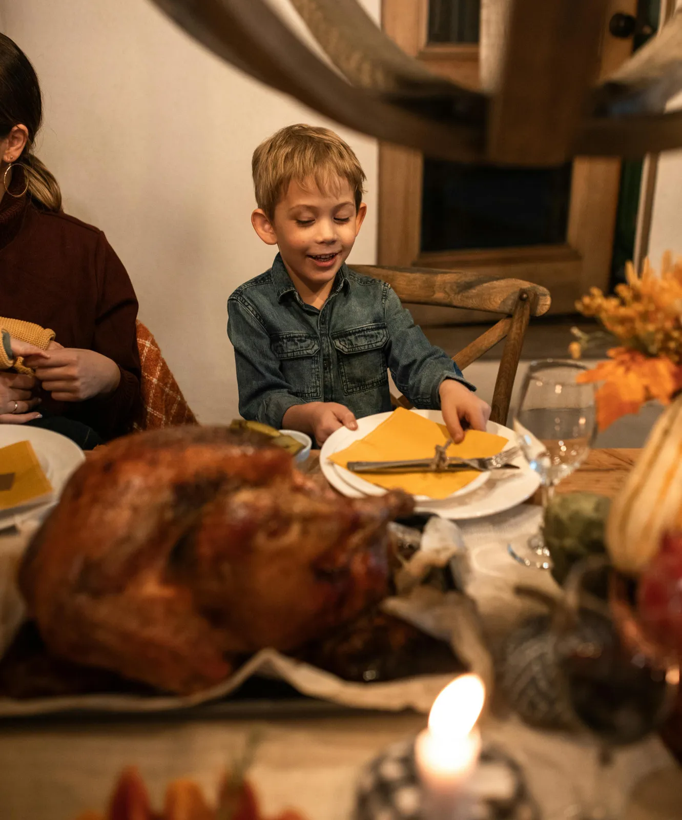 Un niño alrededor de la mesa de Acción de Gracias con su familia, compartiendo sonrisas y actividades de gratitud