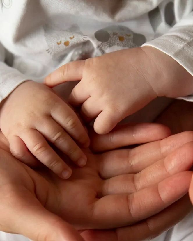 Mamá sosteniendo las manos de su bebé