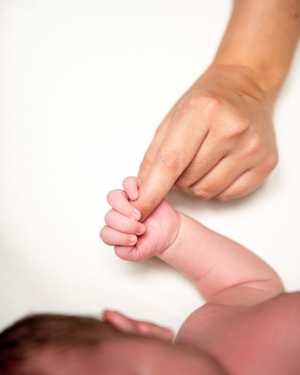 Mano de un bebé recién nacido sujetando el dedo de un adulto