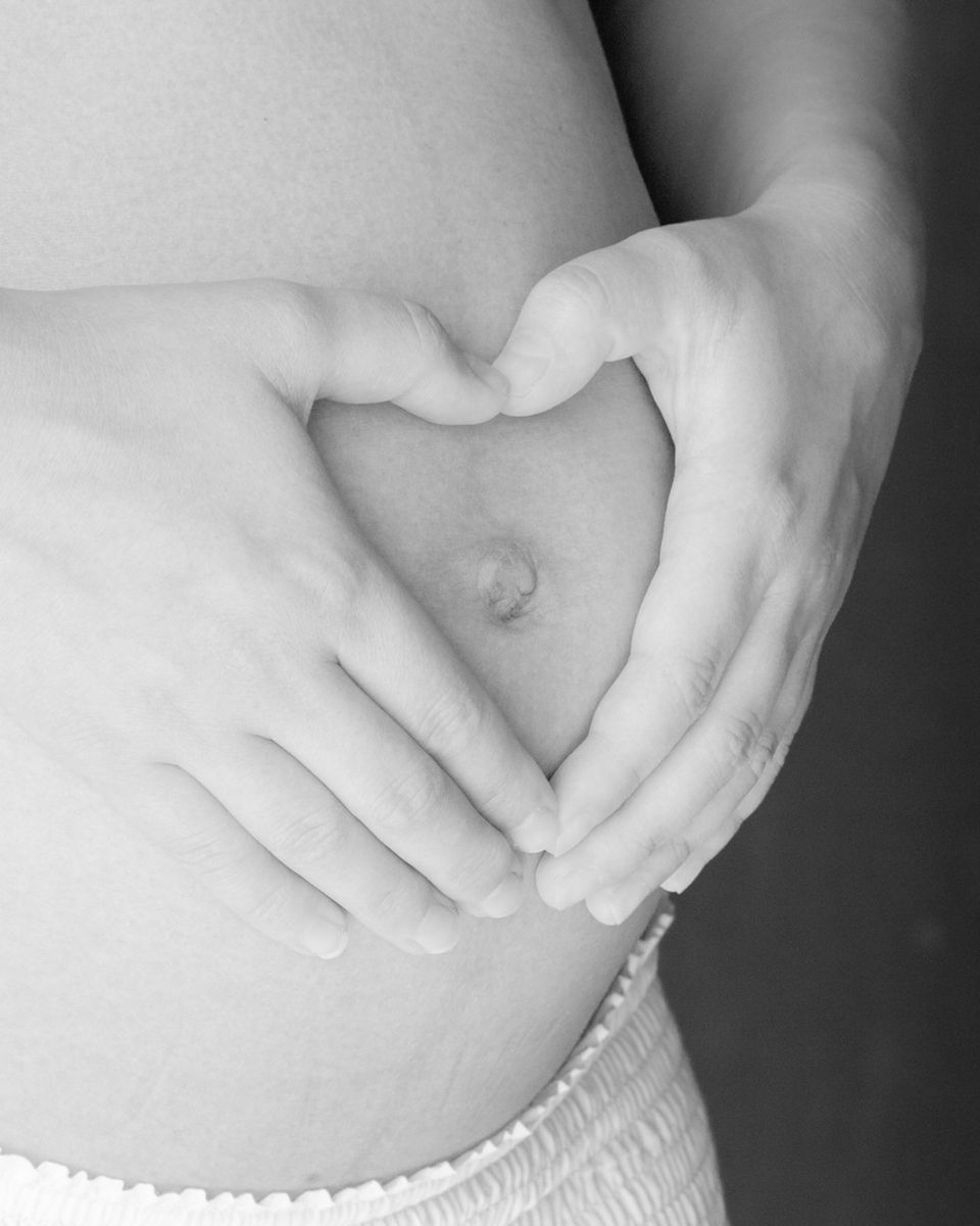 Mujer embarazada formando un corazón con sus manos sobre el vientre